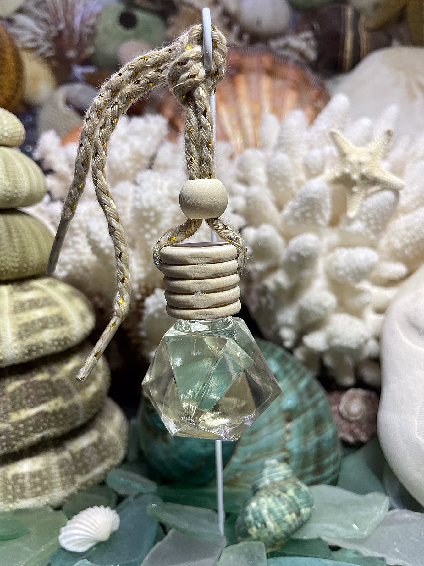 Car diffuser with rope + wood cap (flat lay photo): Small-batch car aroma diffuser with coastal fragrance oil and wood cap on rope hanger.