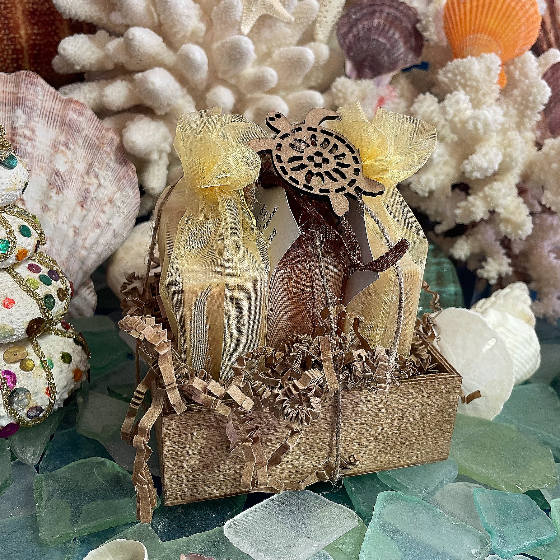 Gift set of three handmade goat milk soaps, two with honey and one plain goat milk, wrapped in sheer organza bags and arranged in a wooden box with crinkle paper.