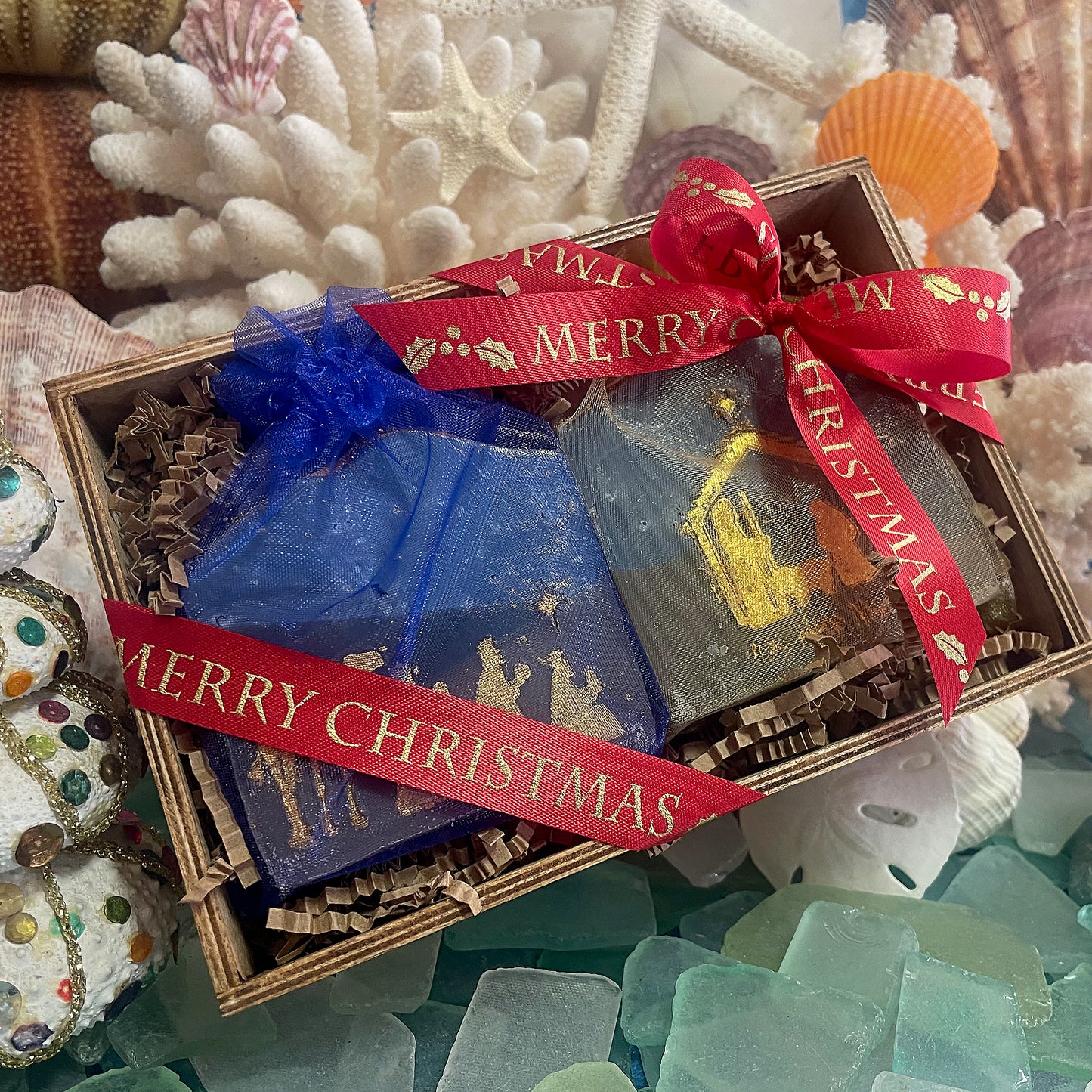 Nativity soap gift set with two handcrafted bars in organza bags, tied with a red “Merry Christmas” ribbon in a wooden box